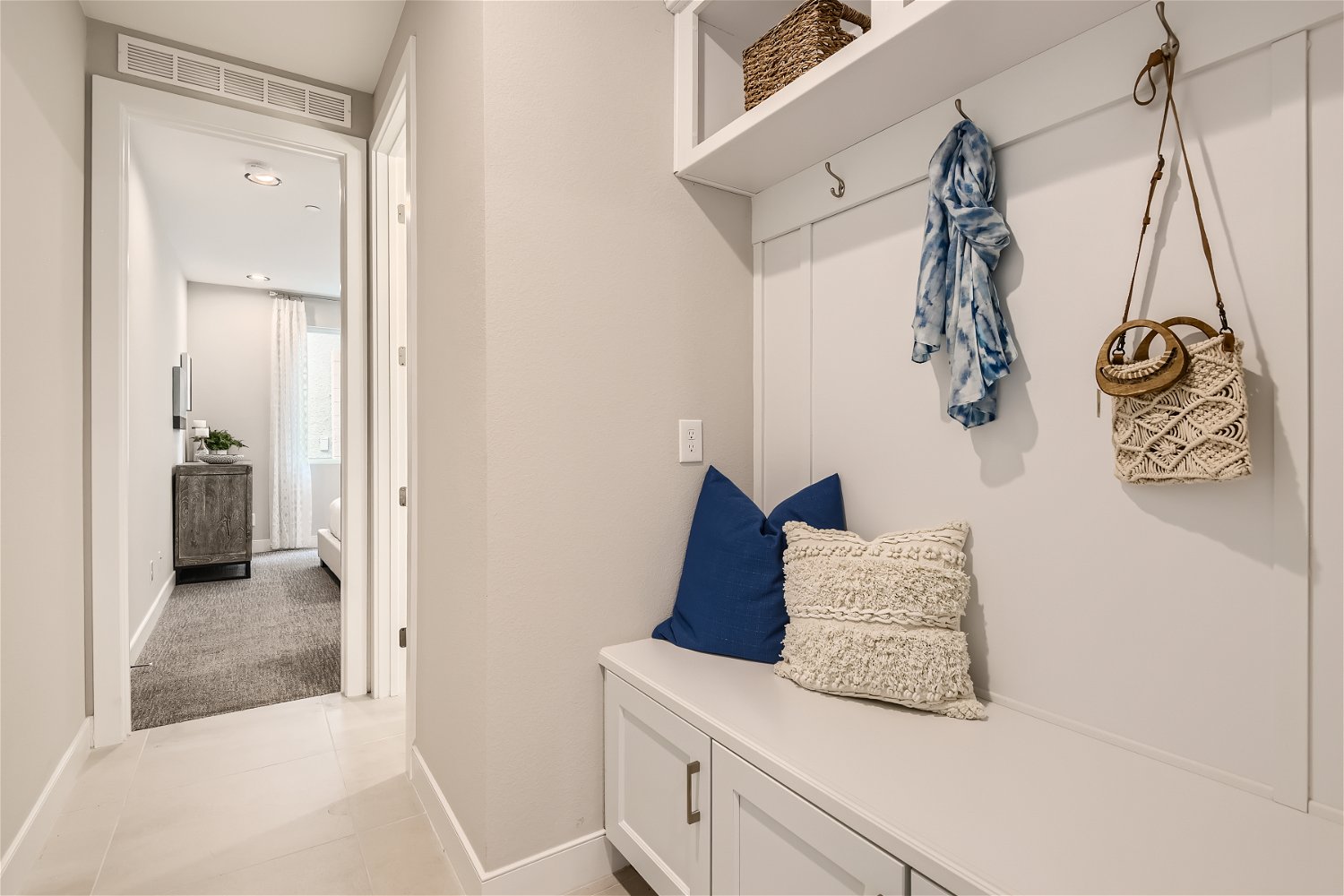 A room with white walls and a white shelf with a blue pillow.