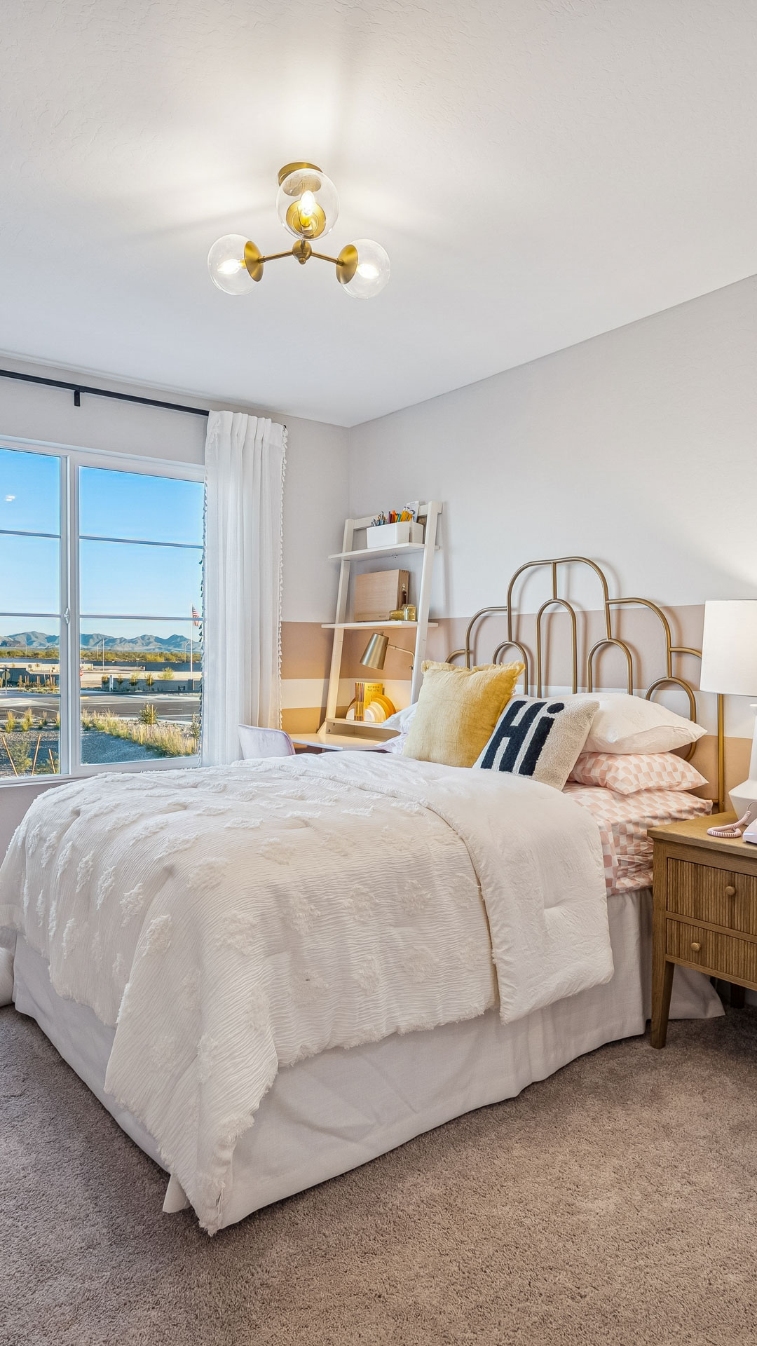 Stunning Pink and white themed bedroom with gold iron daybred & study desk with view of the white tank mountains outside the window at Manzanita at Teravalis Ponderosa model home in Buckeye AZ New Homes for sale and new construction in buckeye AZ. 