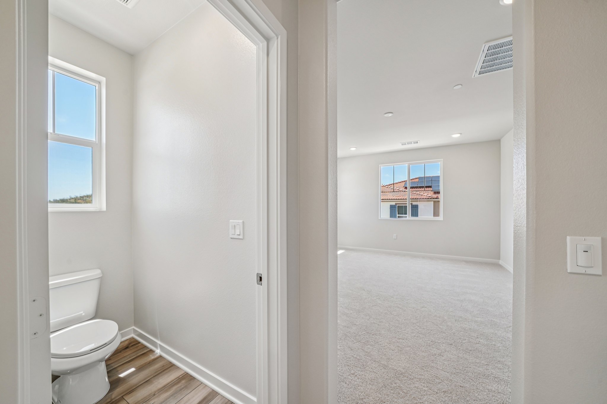 A bathroom with a toilet and a window.