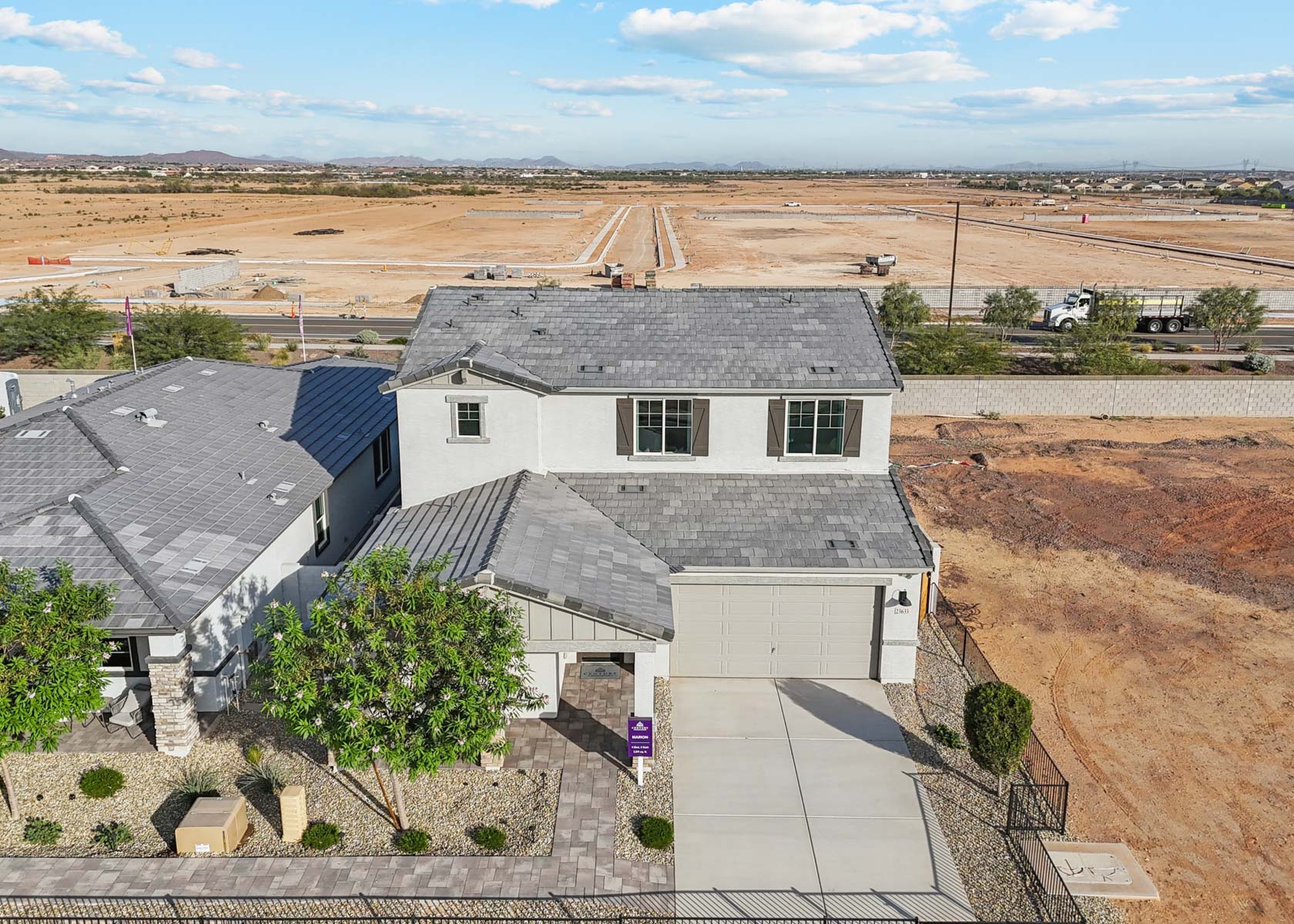 A house with a dirt field and trees in the background.