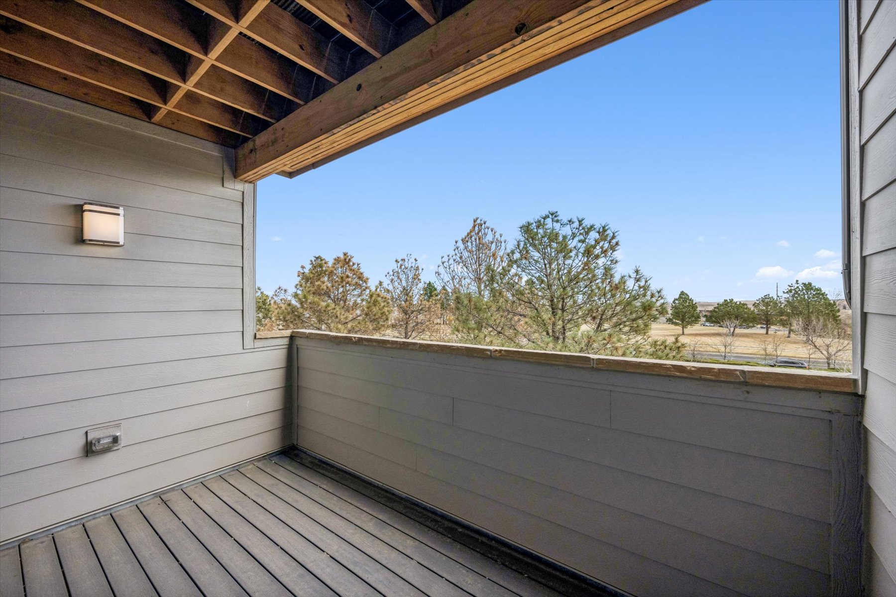 A deck with a wood railing and trees in the background.