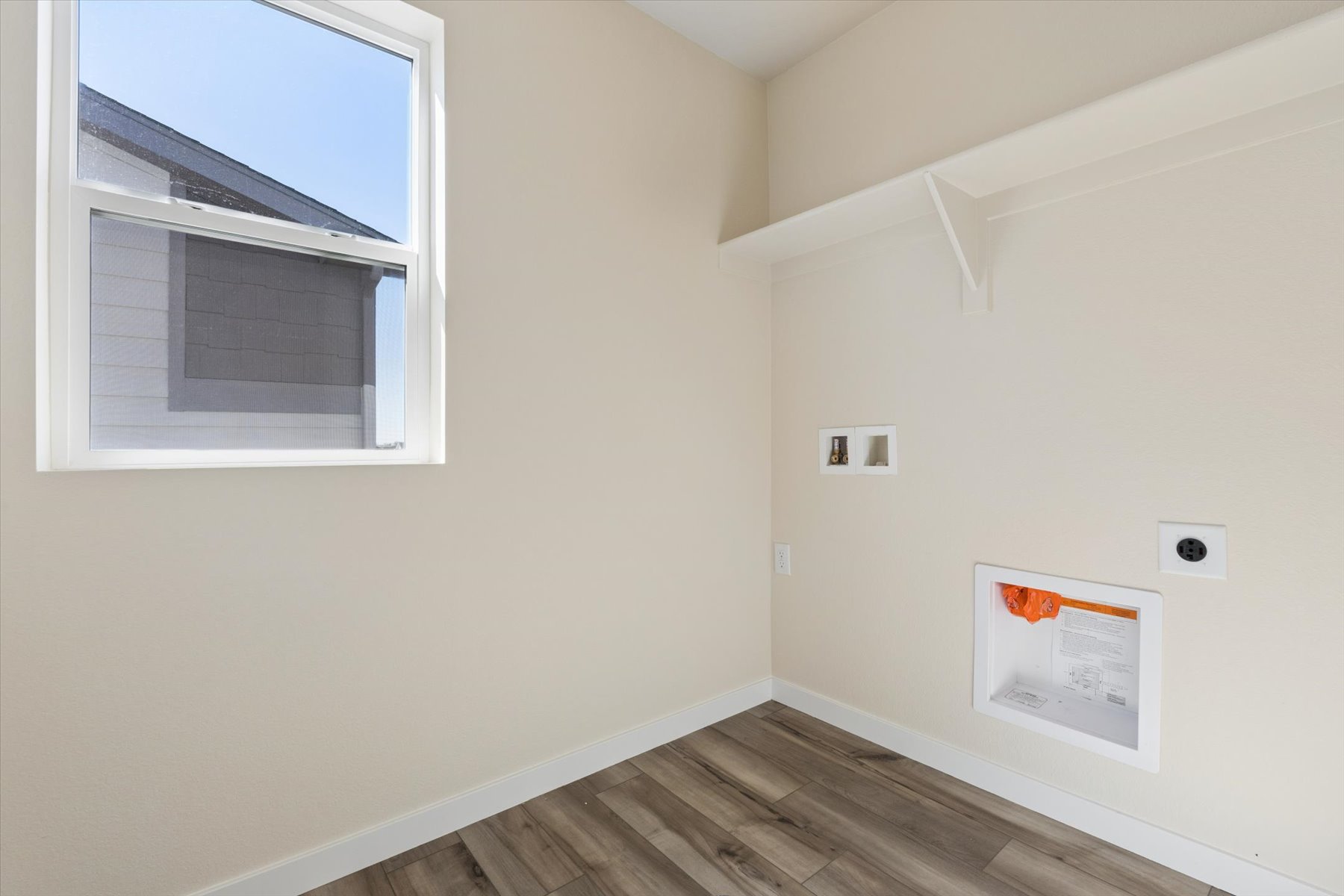 A room with a wood floor and a window with a sign on it.