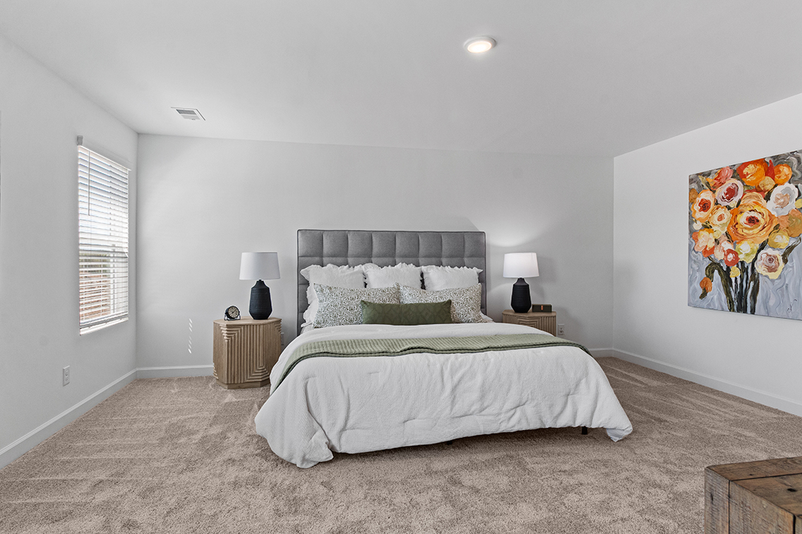 A bedroom with a bed and lamps.