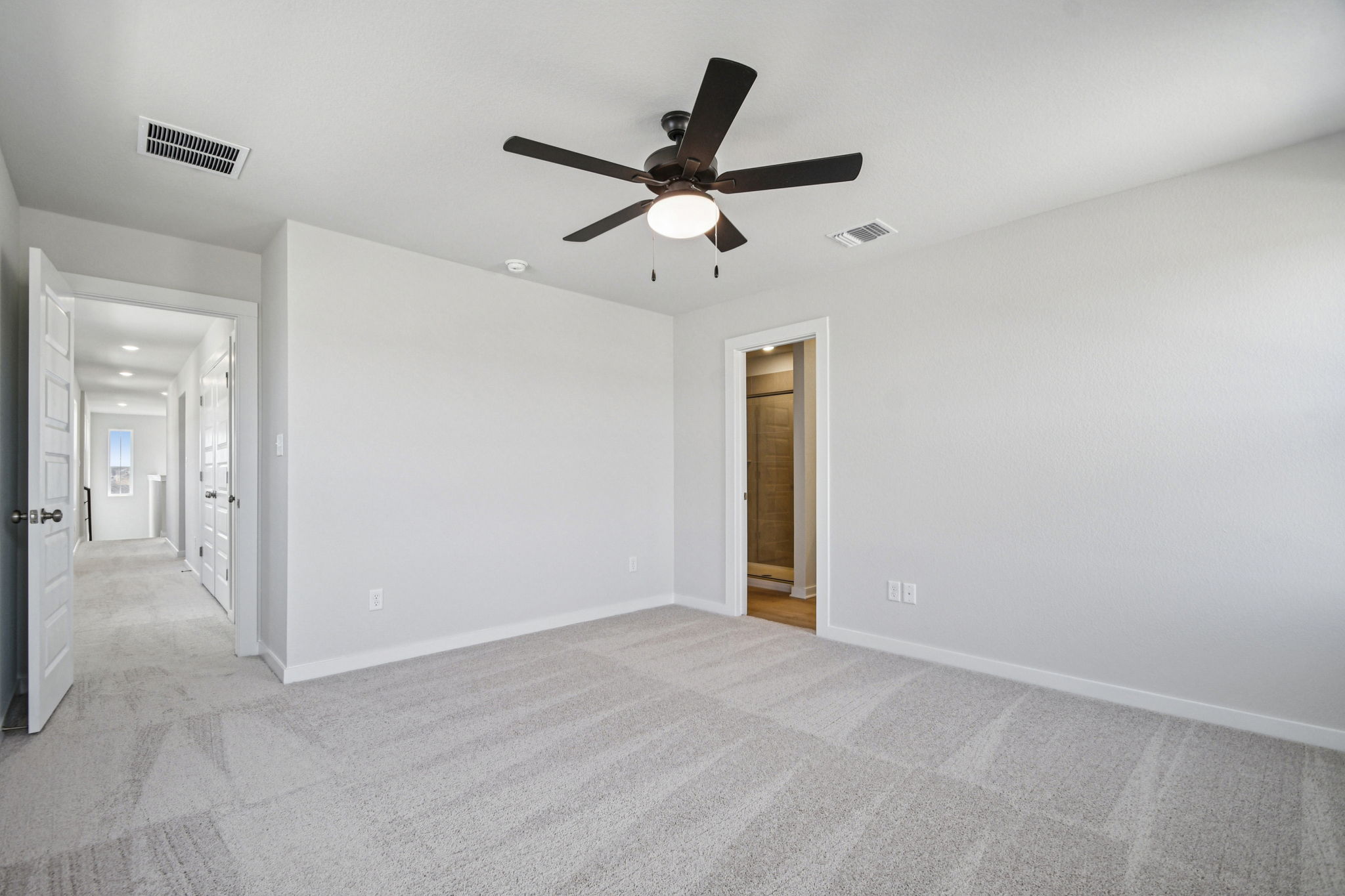 A room with a ceiling fan and a door.
