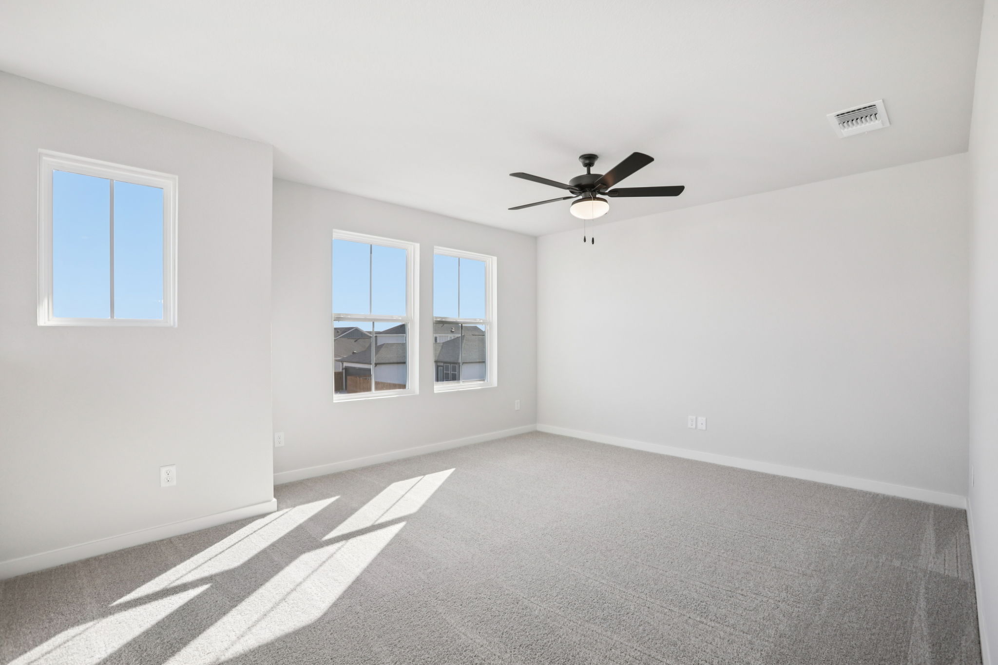 A room with a ceiling fan and windows.