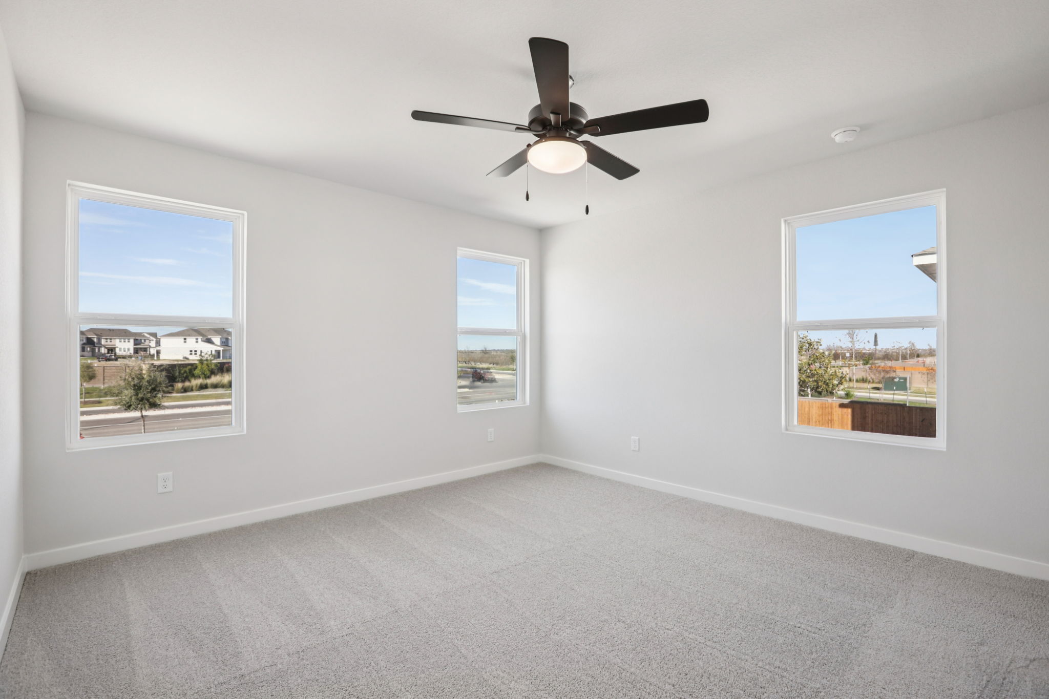 A room with a ceiling fan and windows.