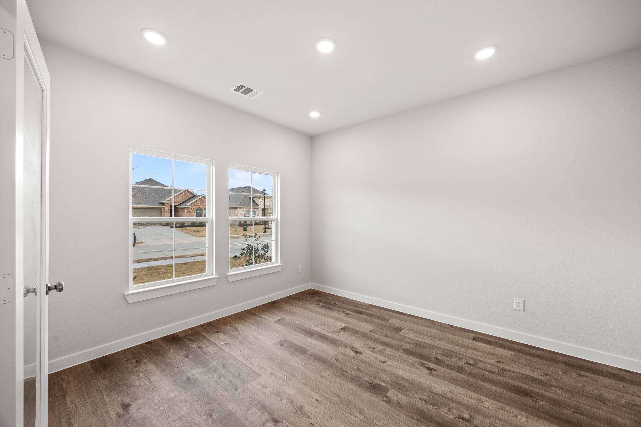 A room with a wood floor and a window with a view of a city.
