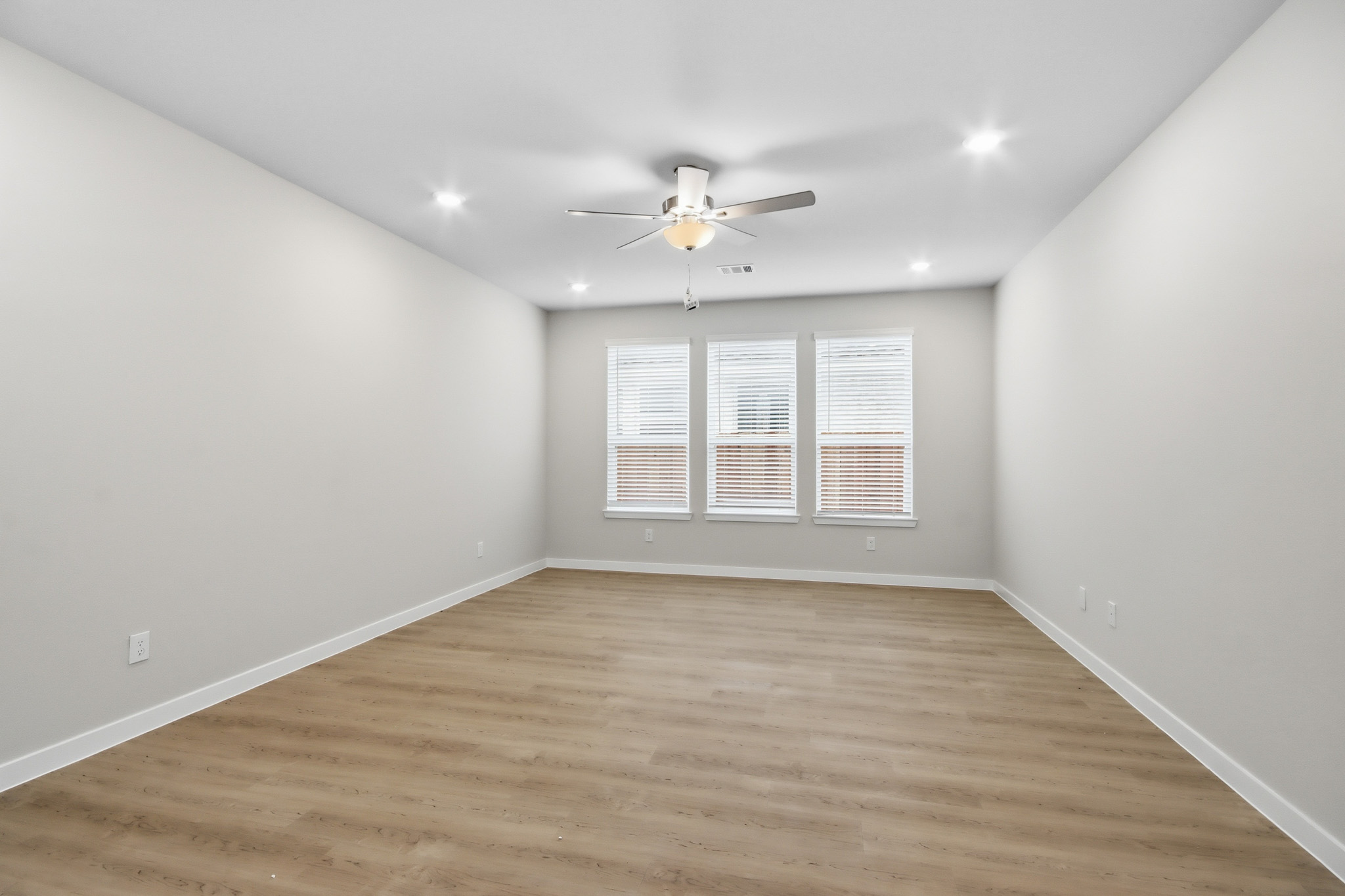 A room with a ceiling fan and a wood floor.