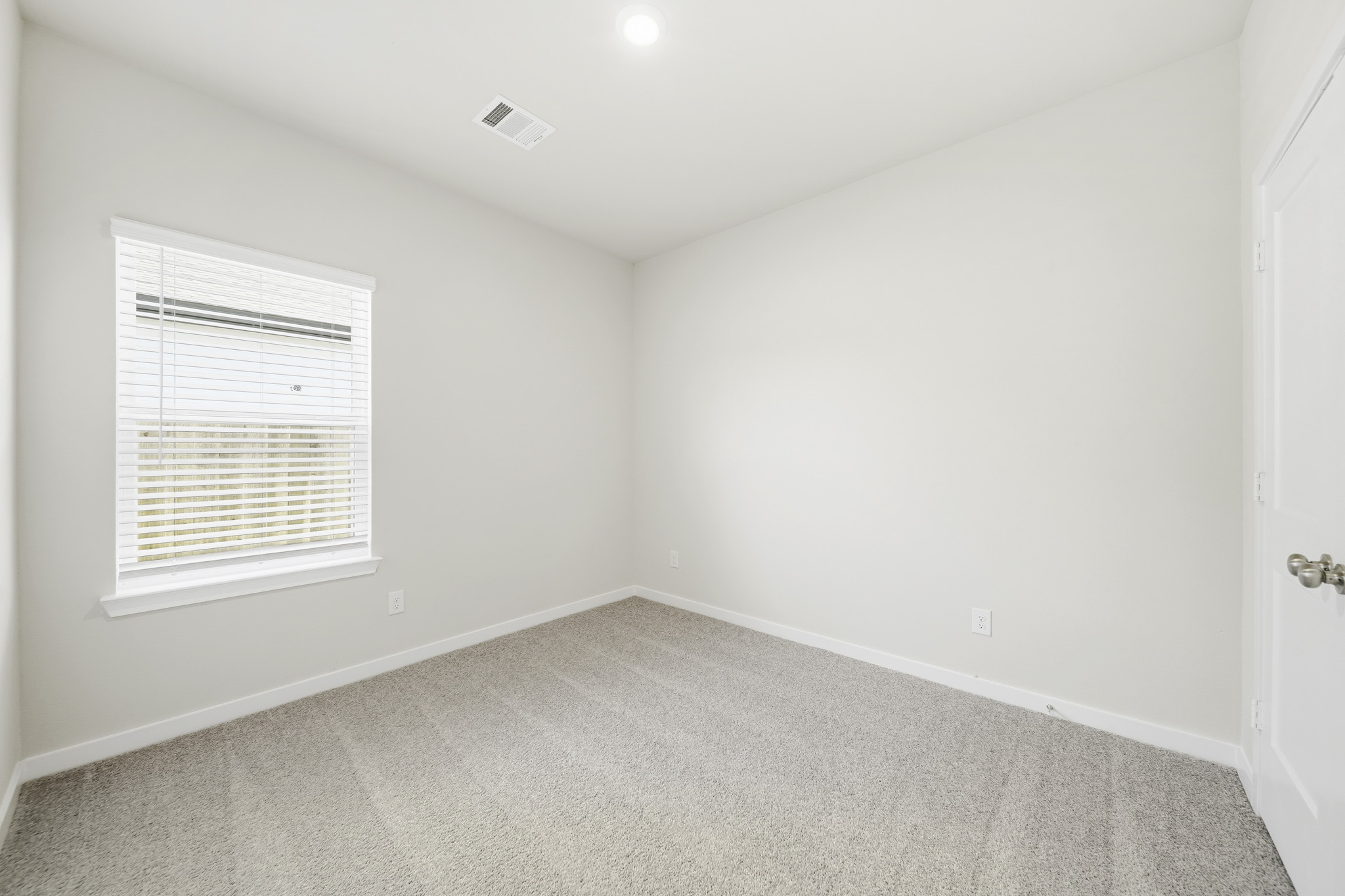 A room with a carpet and a window.