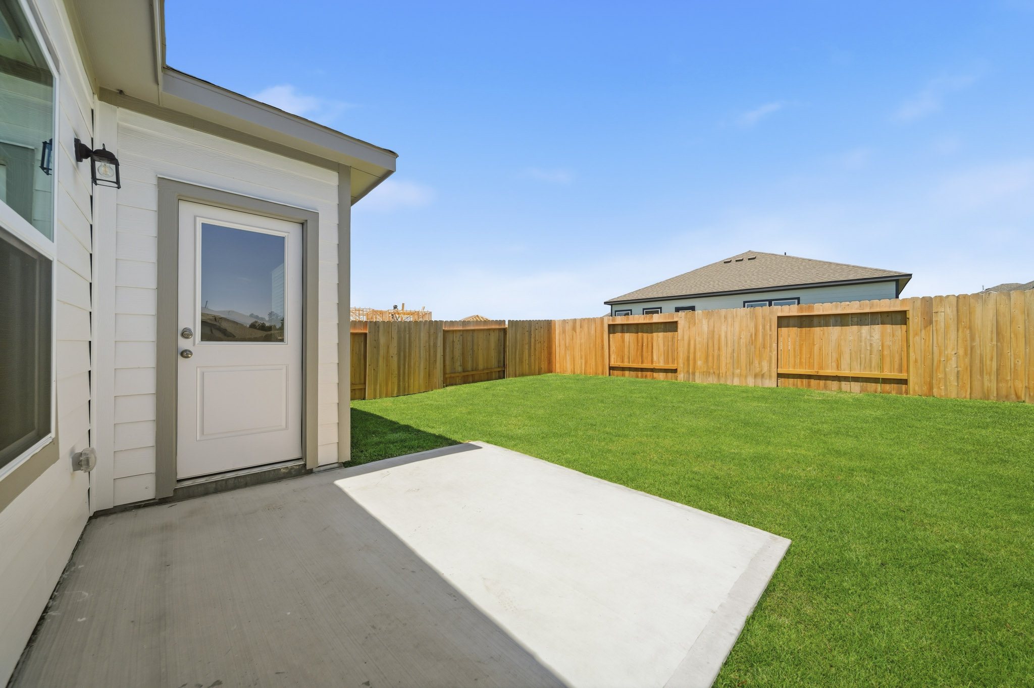 A backyard with a fence and a house.