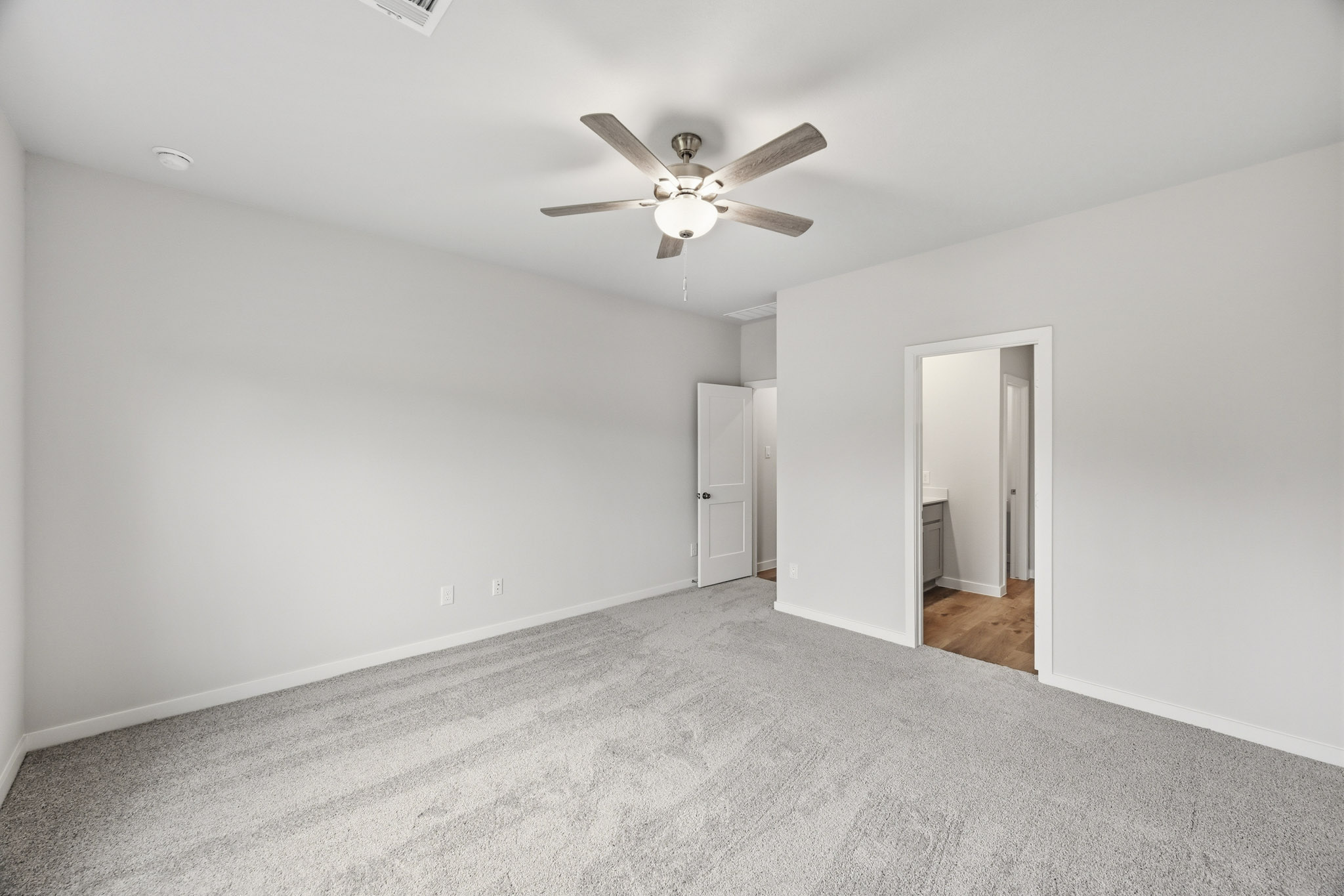 A room with a ceiling fan and a door.