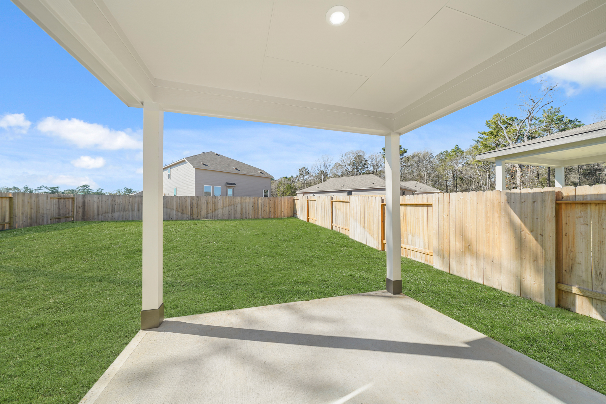 A fenced in yard with a covered area and a wood fence.