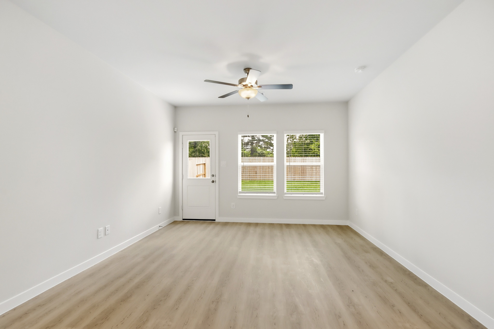 A room with a ceiling fan and a wood floor.
