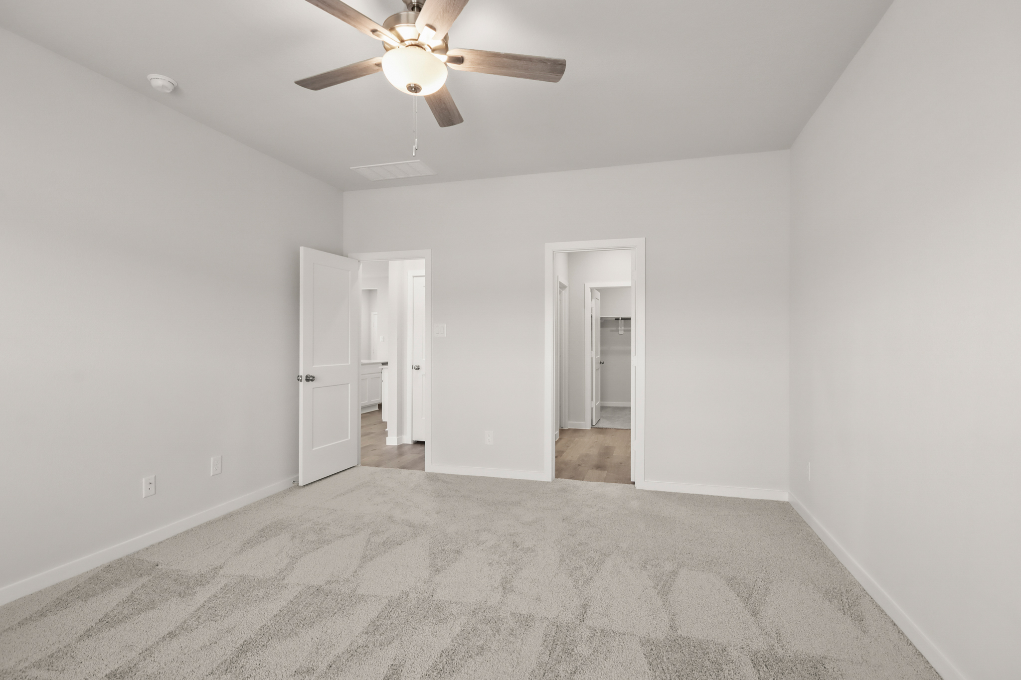 A room with a ceiling fan and a door.