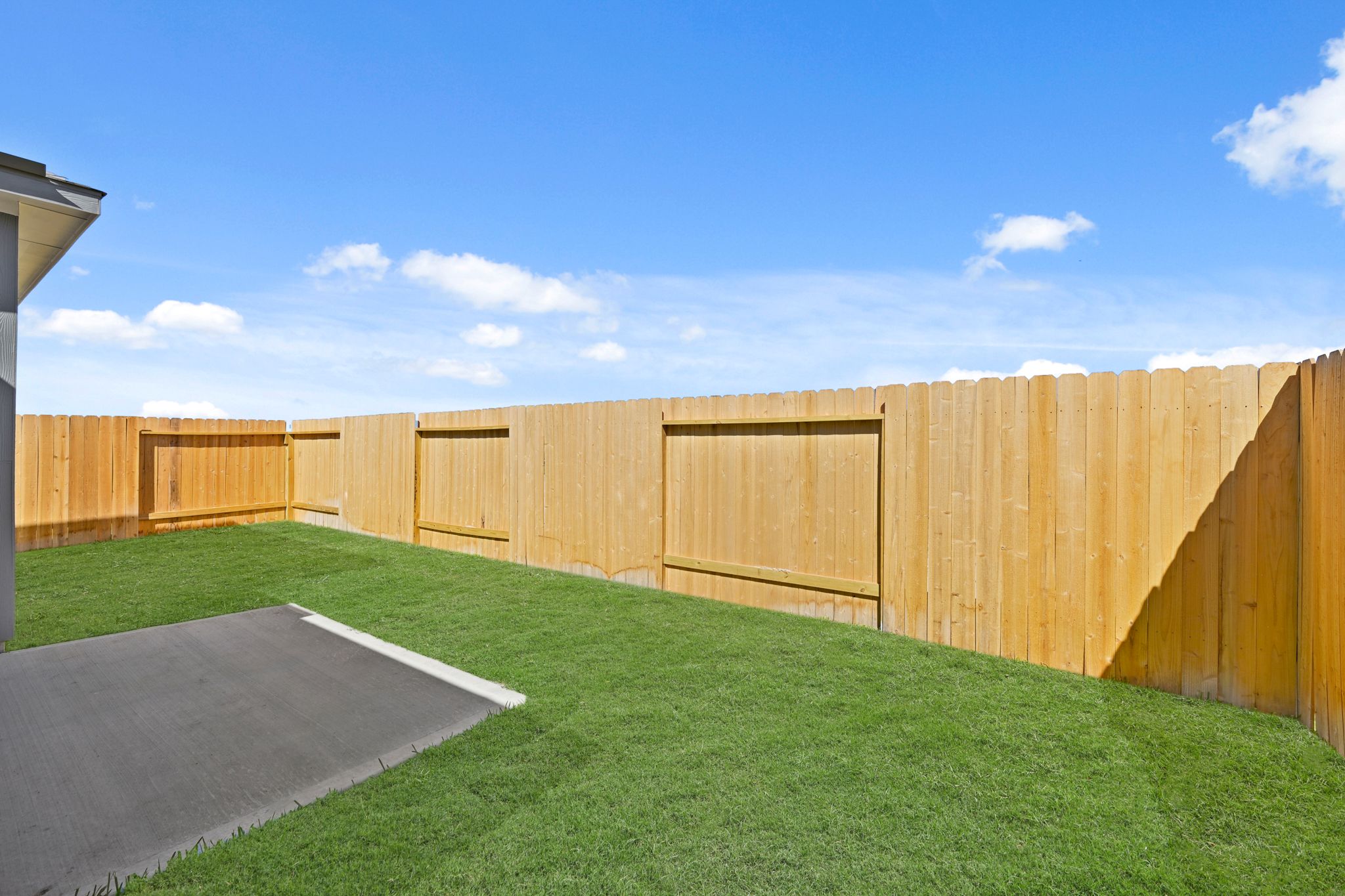 A fenced in area with a grass field and a building in the background.