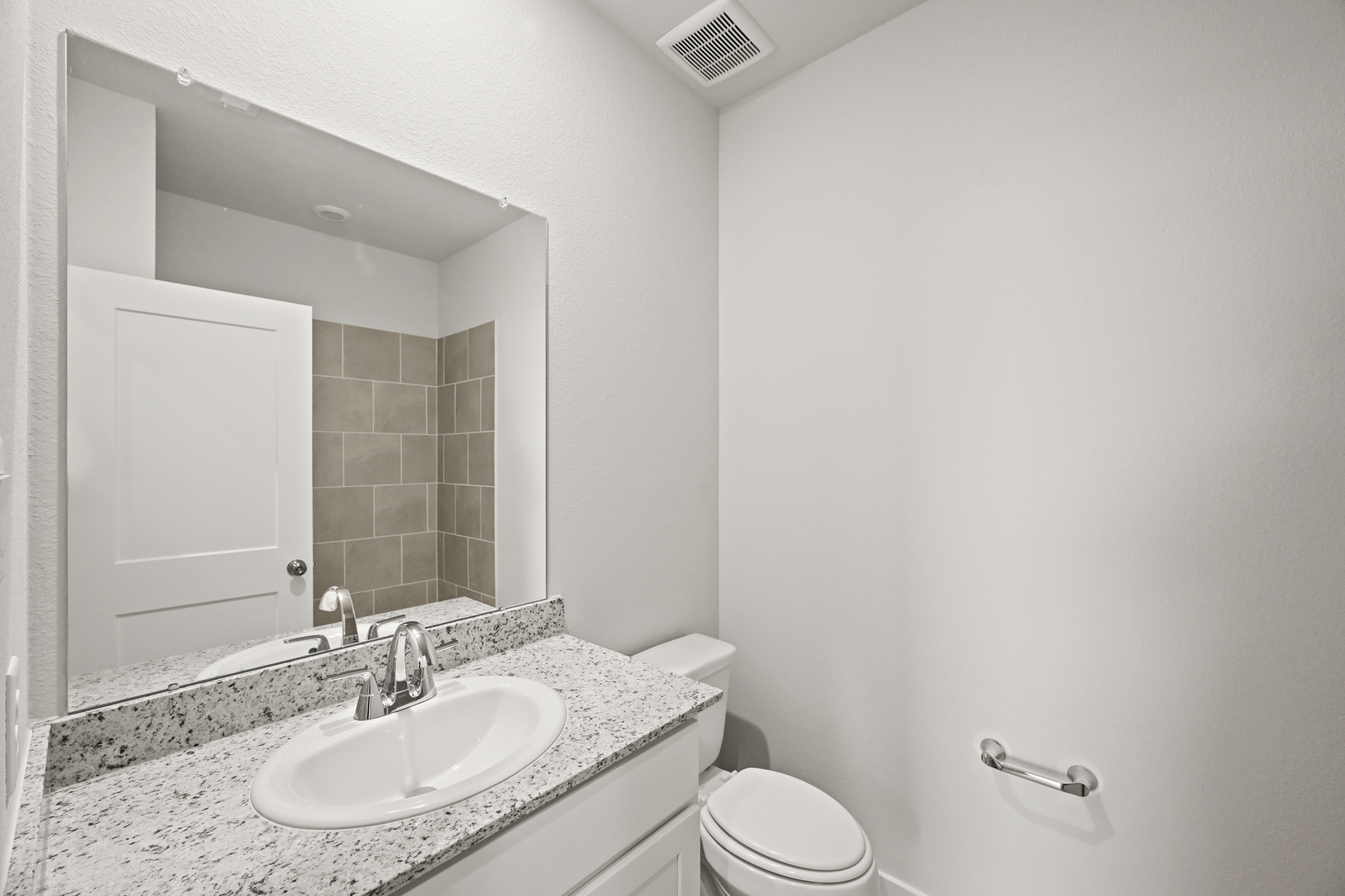 A bathroom with a large mirror.