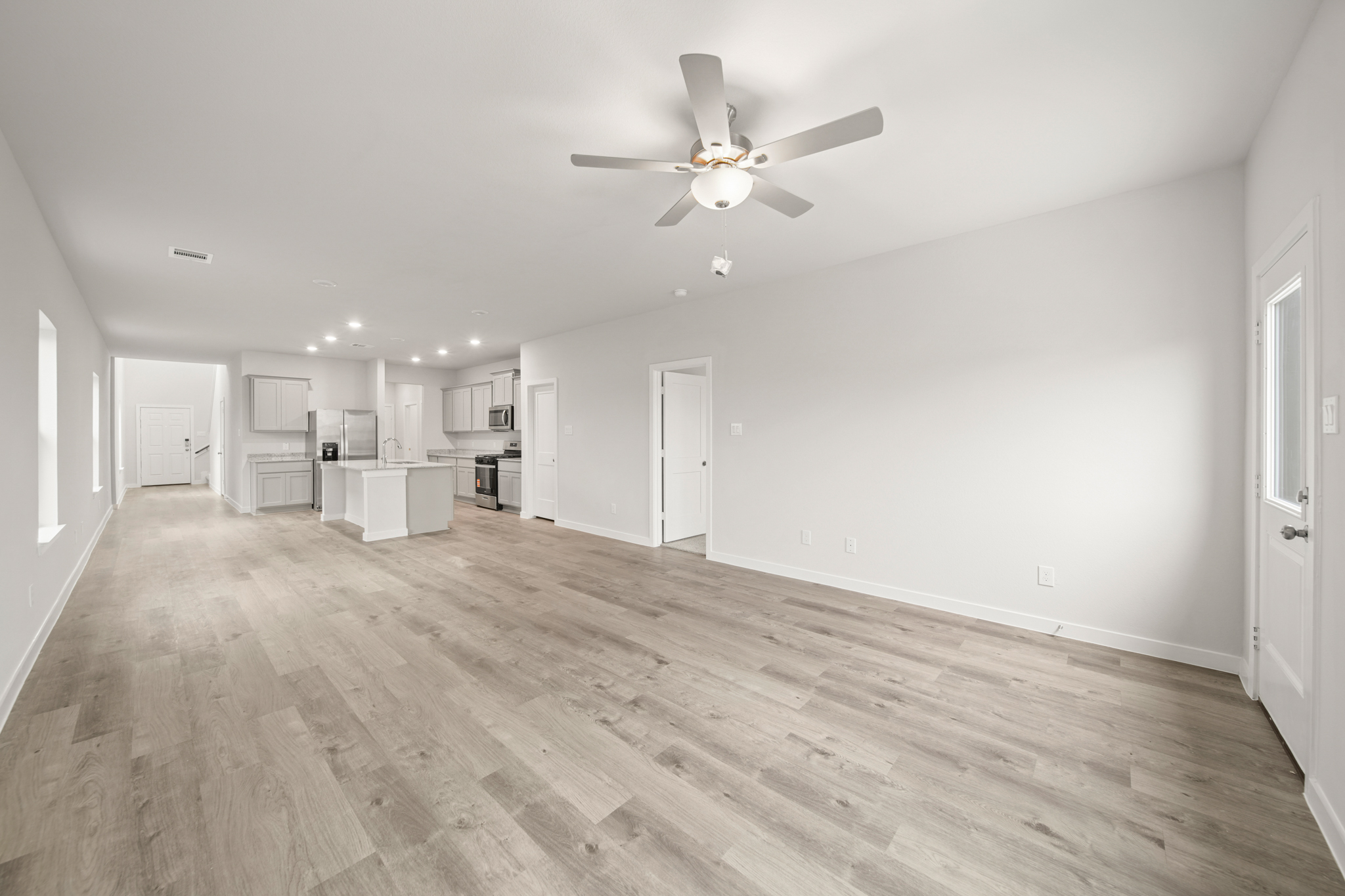 A large empty room with a ceiling fan and a wood floor.