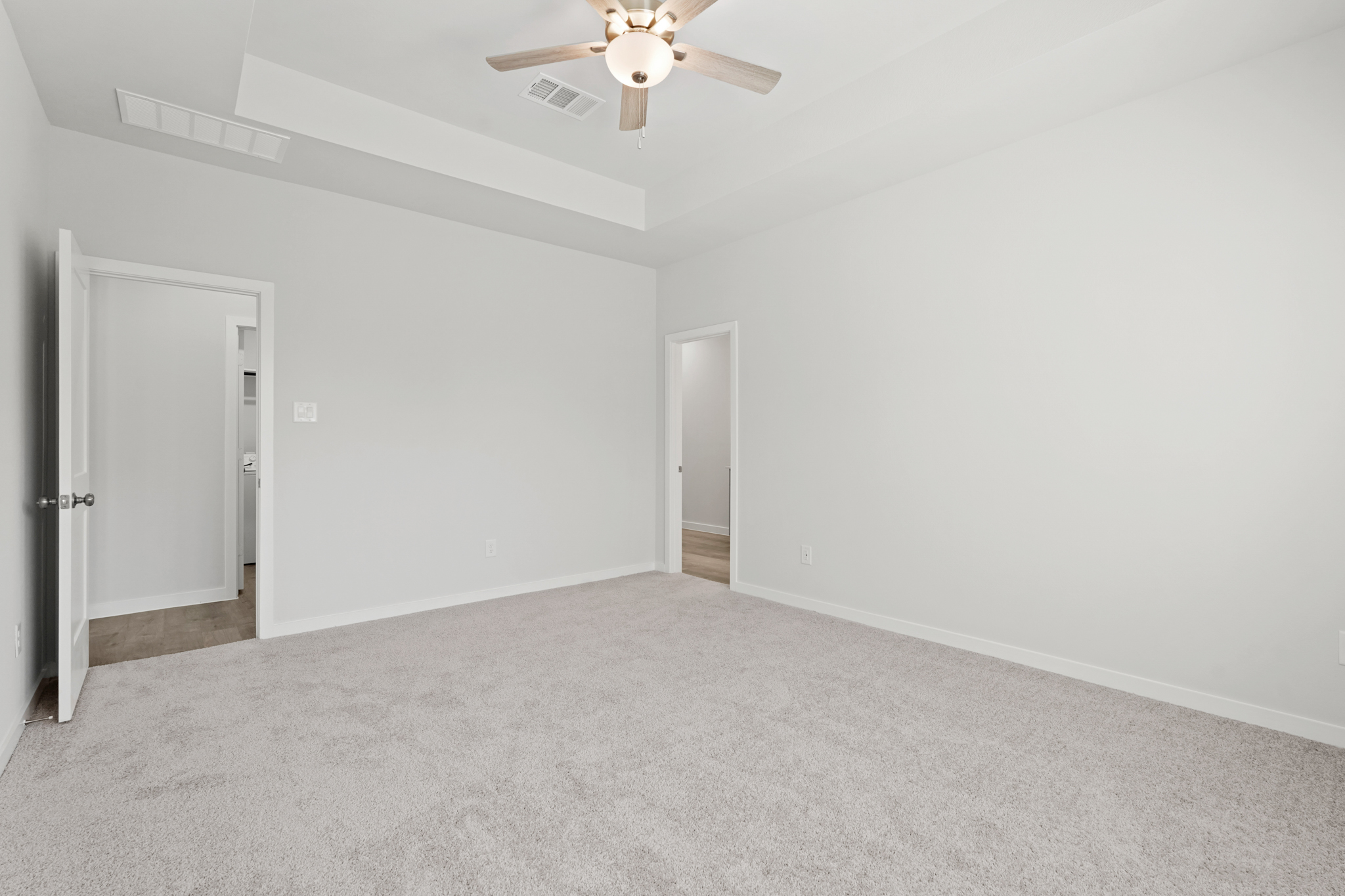 A room with a ceiling fan and a door.