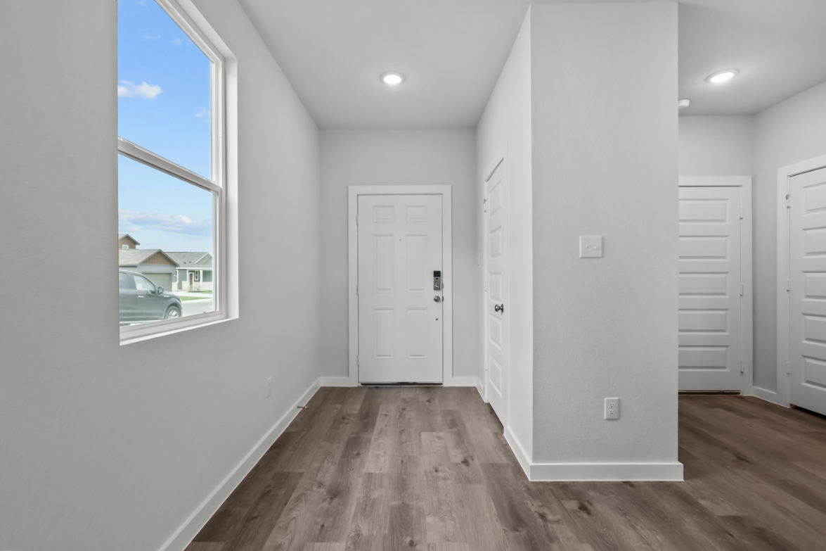 A room with white walls and a wood floor with a window.