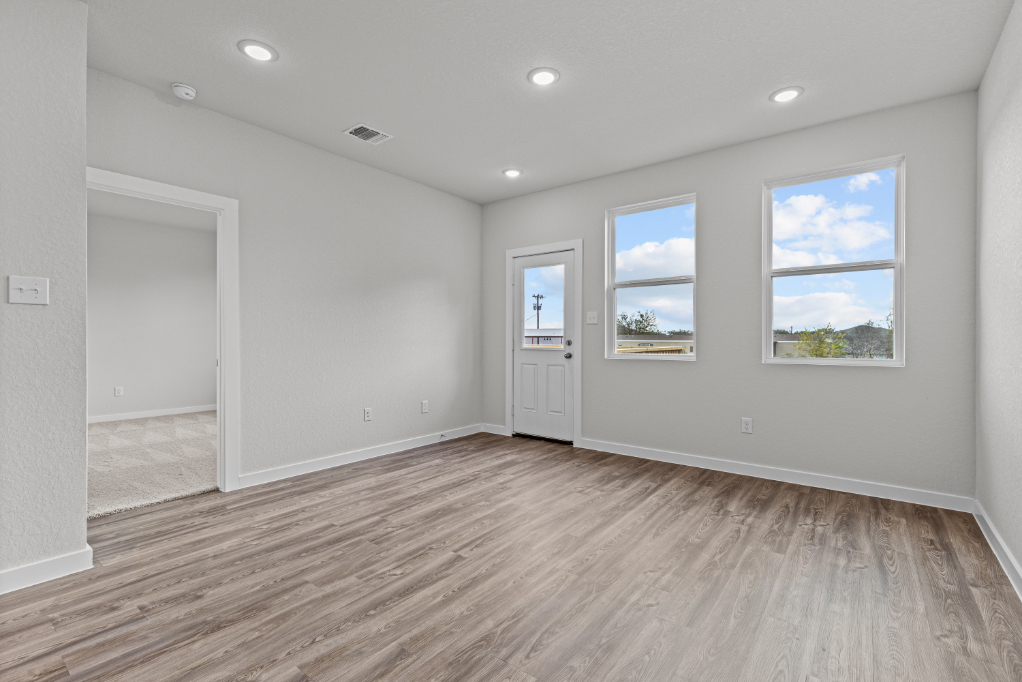 A room with a wood floor and a wood floor with a white door.